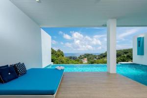 Un dormitorio con una cama azul y una piscina en Amala Grand Bleu Resort Hilltops - SHA, en Kamala Beach