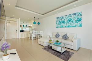 Amala Grand Bleu Resort Hilltops - SHA في شاطئ كامالا: غرفة معيشة مع أريكة بيضاء وطاولة