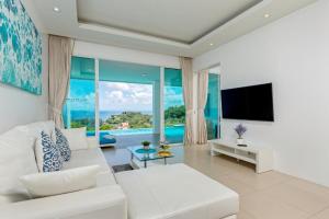 uma sala de estar com um sofá branco e uma televisão em Amala Grand Bleu Resort Hilltops - SHA em Praia de Kamala