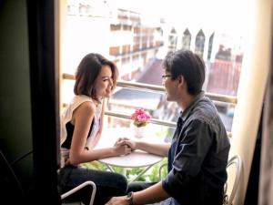 a man and woman sitting at a table in front of a window at Klang Muang @ Nongkhai Hotel in Nong Khai