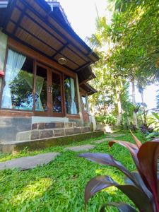 une maison dotée d'une terrasse couverte avec de l'herbe verte dans l'établissement Anandinii River Lodge, à Sidemen