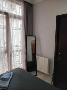 1 dormitorio con espejo, cama y ventana en Apartment Face en Batumi