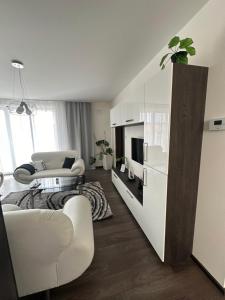 a living room with white furniture and a kitchen at Panorama Apartments Presov in Prešov