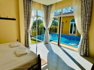 a bedroom with a bed and a large window with a pool at KHAO YAI MY WAY in Ban Tha Chang