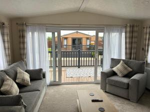 a living room with a couch and an open door at Kingfisher Lodge Long Acre Holiday Park in Evesham