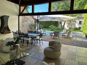 eine Terrasse mit einem Tisch, Stühlen und einem Sonnenschirm in der Unterkunft Maison coup de cœur in Fauverney