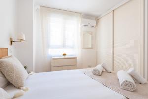 - une chambre blanche avec un lit et des serviettes dans l'établissement MalagaSuite Malagueta Beach & Sun, à Malaga
