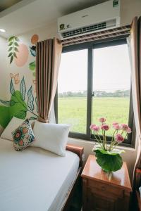 a bedroom with a bed and a window with flowers at Tam Coc Ninh Binh Bungalow in Ninh Binh