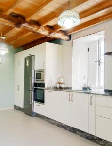 a kitchen with white cabinets and a wooden ceiling at Casa Lolita 1 in Viveiro +36 photos