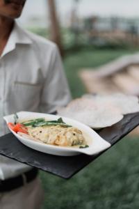 باكووتر ريبليس كوماراكوم في كوماراكوم: شخص يحمل طبق من الطعام على طاولة