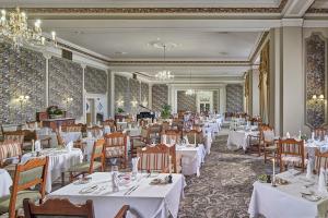 una sala da pranzo con tavoli e sedie bianchi di The Grand Hotel a Eastbourne