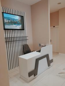 Habitación con escritorio blanco y TV en la pared. en Hotel Restaurant Univers en Shkodër