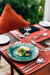 eine blaue Platte mit Essen auf einem Tisch mit Besteck in der Unterkunft Cinnamon Hakuraa Huraa Maldives - All Inclusive in Meemu Atoll