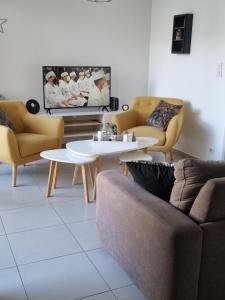 ein Wohnzimmer mit einem Sofa, Tischen und einem TV in der Unterkunft MAGNIFIQUE APPARTEMENT LES PIEDS DANS L'EAU PROPRIANO in Propriano