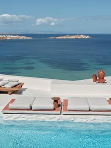 a swimming pool with lounge chairs and the ocean at Boheme Mykonos Town - Small Luxury Hotels of the World in Mikonos