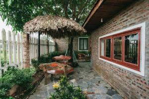 a patio with an umbrella and a chair and a table at Tam Coc Ninh Binh Bungalow in Ninh Binh