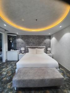 1 dormitorio con 1 cama blanca grande y 1 reposapiés grande en Kay Hotel Da Nang, en Da Nang