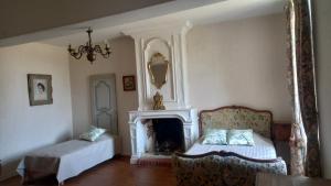 a bedroom with a fireplace and a bed and a chair at Gite du Manoir des Anoteux in Carneville