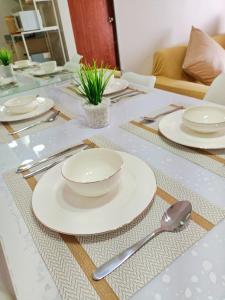 a table with white plates and spoons on it at The Hive tower D with pool, Wifi, and balcony in Taytay