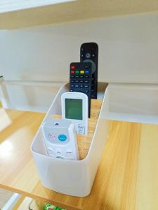 a plastic container with a cell phone and remote controls at The Hive tower D with pool, Wifi, and balcony in Taytay
