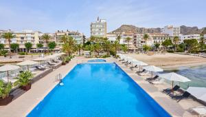 a pool with chairs and umbrellas next to a beach at Hoposa Daina- Adults Only in Port de Pollensa