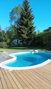 een zwembad met een boom en een houten dek bij Exklusive villa on the coast close to Stockholm in Åkersberga