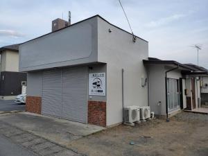 a white building with a door and a microwave at 鐡ノ家　分家 in Fuefuki