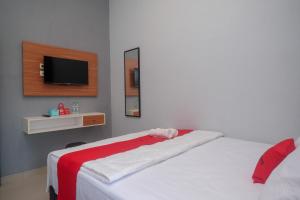 a bedroom with a bed with a tv on the wall at RedDoorz Near Dr Oen Solo Baru Hospital in Klaten