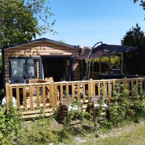 une cabine avec une clôture en bois et un parasol dans l'établissement Casa Gera Lauwersoog, à Lauwersoog