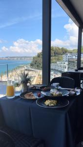 - une table avec des assiettes de nourriture et une vue sur l'océan dans l'établissement Belvedere Hotel, à Vlorë