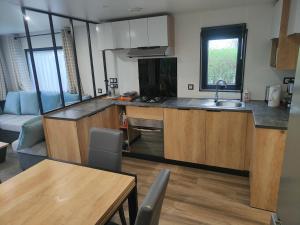 a kitchen with wooden cabinets and a table and a couch at Casa Gera Lauwersoog in Lauwersoog
