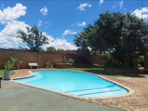 a swimming pool in a yard with a brick wall at Johannesburg Airport Hostel in Benoni