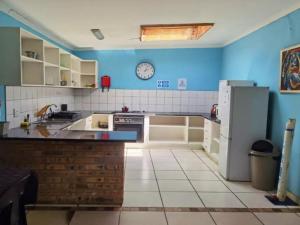 Johannesburg Airport Hostel في بينوني: مطبخ مع ثلاجة وساعة على الحائط