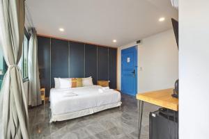 een slaapkamer met een wit bed en een blauwe muur bij Ployburi Boutique Hotel in Chanthaburi