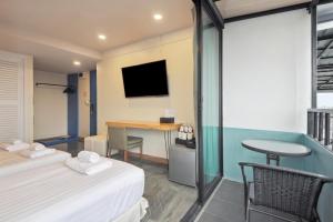 a room with two beds and a desk with a television at Ployburi Boutique Hotel in Chanthaburi