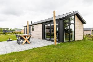 ein kleines Haus mit einer Terrasse und einem Tisch in der Unterkunft Recreatiepark De Bosrand in Oudemirdum
