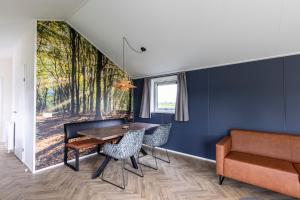 uma sala de jantar com uma mesa e cadeiras e um sofá em Recreatiepark De Bosrand em Oudemirdum