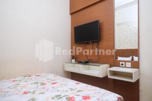 ein Schlafzimmer mit einem Bett und einem TV an der Wand in der Unterkunft Tatti Inn Syariah Seturan RedPartner in Yogyakarta