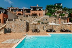 a pool with chairs and umbrellas next to a building at Apelon Tiritas Villas in Leonidion