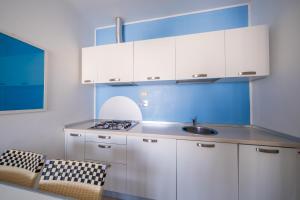 a kitchen with white cabinets and a sink at Solidago Residence in Tirrenia