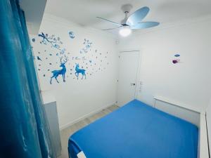 Cette chambre comprend un lit bleu et un ventilateur de plafond. dans l'établissement Piso Lorena 170m playa Wifi aire, à Puerto de Sagunto