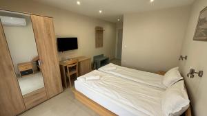 1 dormitorio con 1 cama y escritorio con TV en Семеен хотел Сирена, en Ahtopol