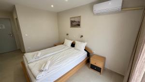 1 dormitorio con 1 cama con sábanas blancas y ventilador en Семеен хотел Сирена, en Ahtopol