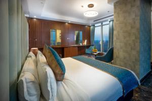 ein Schlafzimmer mit einem großen weißen Bett mit blauen Kissen in der Unterkunft Donatello Jeddah Hotel in Dschidda