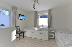 a bedroom with two beds and a tv and two windows at Haus Prohl Whg1 in Dahme