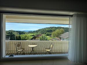 a balcony with two chairs and a table and a window at Ferienwohnung Terkl in Velden am Wörthersee