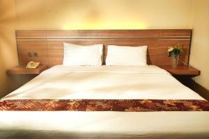 a bedroom with a large bed with two pillows at Gapura Residence Airport Semarang by Sinergi in Semarang