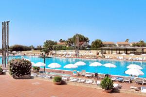 a large swimming pool with white umbrellas and chairs at L'Oasi di Athena in Ragusa
