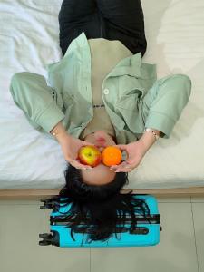 una mujer está sosteniendo fruta en la parte superior de una cama en Gapura Residence Airport Semarang by Sinergi, en Semarang