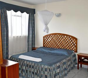 1 dormitorio con 1 cama con manta azul y ventana en YWCA Parkview Suites, en Nairobi